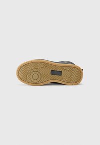Zwarte sneakersoled met een gestructureerde gumrubberen buitenzool. Bevat cirkelvormige en golvende patronen voor tractie. Kenmerkende rechthoekige Accent.
