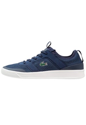 Granatowy sneaker z siateczkową i materiałową cholewką, białą podeszwą, sznurowaniem, pętelką na pięcie i języku oraz zielonym logo krokodyla z boku.
