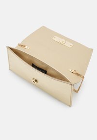 Clutch metallico oro con finitura testurizzata, dotato di una tracolla a catena, chiusura a scatto e un interno beige con etichetta.
