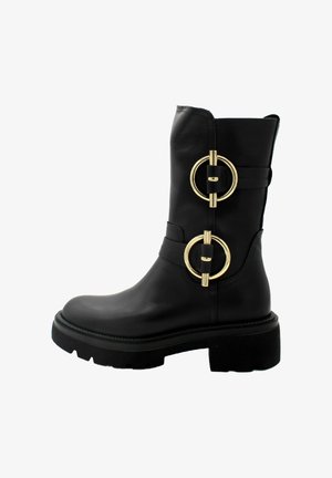 Botte de cheville en cuir noir avec deux accents en métal doré circulaires, talon épais et semelle texturée. Design épuré avec des détails de couture minimaux.