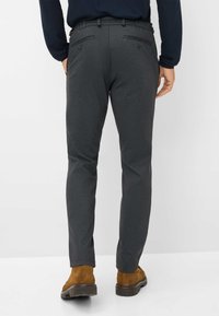 Grijze geblokte broeken met een slim fit, voorzien van twee achterzakken met knopen, gedragen met bruine suède enkellaarsjes. Glad stofmateriaal.