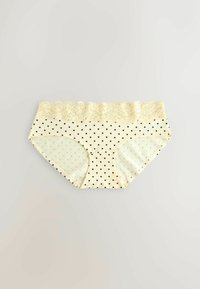 Culotte pour femme couleur crème avec des pois noirs et une large ceinture en dentelle, posée à plat sur un fond neutre.