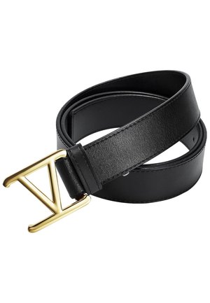 Musta nahkavyö rullattuna, jossa kiiltävä kultainen metallisolki kirjaimen V muotoinen.
