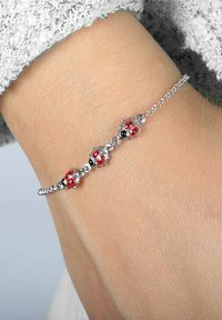 Bracciale d'argento con tre ciondoli a forma di coccinella, con dettagli rossi e neri, collegati da una delicata catena, indossato su un polso.