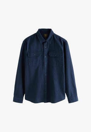 Tumši zila garām piedurknēm krekls ar pogām, izgatavots no strukturētas auduma, ar divām krūšu kabatām un punktveida apkakli ar vienas pogas aprocēm.