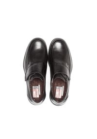 Zapatos de cuero negros con un diseño redondeado, que cuentan con una correa de velcro, interior acolchado y costuras en contraste a lo largo de los bordes.