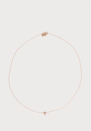 Collier délicat en chaîne d'or avec un petit pendentif en forme de croix et un fermoir à ressort sur fond blanc.