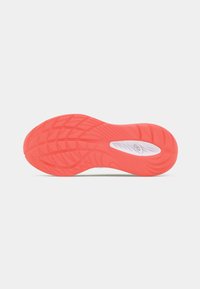 Semelle d'une chaussure, présentant une surface en caoutchouc rouge texturé avec un motif ondulé et un accent blanc au talon.