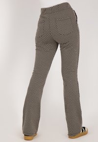 Zwart-witte gemusterde uitlopende broek met een hoge taille en zijzakken, voorzien van een gestructureerd ruitpatroon en een gladde afwerking.