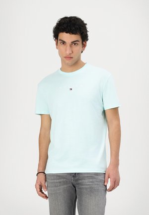 Lyseblå bomulds T-shirt med rund hals, korte ærmer og logo teksten "TOMMY JEANS" foran i kontrastfarver. Båret med grå jeans.