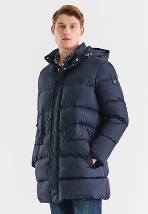 Granatowa kurtka puchowa z kapturem, zamkiem błyskawicznym z przodu, zatrzaskami, dwiema dużymi kieszeniami oraz pikowaną fakturą. Zewnętrzny materiał wydaje się błyszczący.
