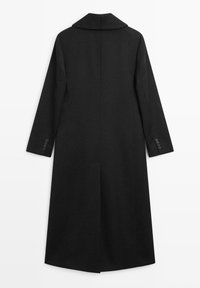Černý vlněný kabát se širokým límcem, dlouhými rukávy a přímým střihem. Má knoflíkové detaily na manžetách a zadní rozparek pro lepší pohyb.