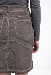 Szara spódnica z denimu o dopasowanym fasonie, z wysokim stanem, tylnymi kieszeniami, teksturowaną tkaniną i wyraźnymi przeszyciami.