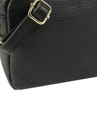 Zwarte leren handtas met een gestructureerde afwerking en een goudkleurige metalen gesp op de band, met een afgeronde basis en subtiele stikdetails.