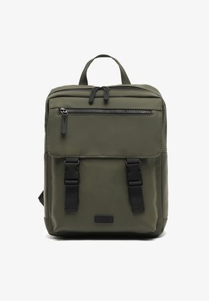 Quadratischer olivgrüner Rucksack mit einer vorderen Reißverschlusstasche, zwei schwarzen Schnallenriemen, einem oberen Griff und einem Hauptreißverschluss.