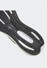 Suola di scarpa da ginnastica in bianco e nero con gomma testurizzata, modelli di battistrada vari e marchio "CLOUDFOAM" sulla midsole.