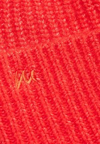 Berretto di lana rossa lavorato a maglia con un motivo testurizzato e un piccolo logo ricamato giallo. Il filato spesso conferisce un aspetto accogliente.