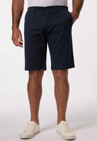 Námořnické modré šortky z bavlněné směsi s knoflíkovým zapínáním, postranními kapsami a rovnými nohavicemi, kombinované s bílými teniskami.