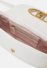 Borsa a mano in pelle bianca con chiusura in metallo dorato, fodera in raso rosa e tasca interna per carte. Texture liscia e design curvo.