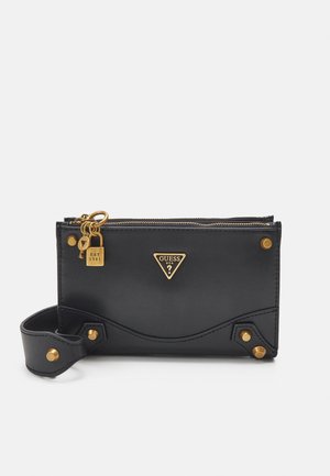 Musta nahkainen lompakko, jossa kullatut metalliosat, logovivahde, vetoketjukiinnitys ja irrotettava rannelenkki. Pohjan lähellä teksturoidut yksityiskohdat.