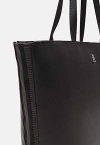 Schwarze Leder-Tote mit glatter Textur und zwei Trägern. Besitzt ein gestreiftes Muster in dunklen Tönen und einen silbernen Logo-Akzent.