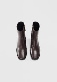 Brown leather ankle boots with a smooth texture, square toe, and side zipper. The sole is black with a rounded edge.