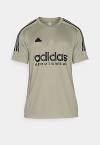 Olivgrön Adidas sporttröja med svarta vertikala ränder på ärmarna, stor text "adidas SPORTSWEAR" och rund halsringning.