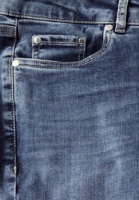 Jeans de denim en un color azul oscuro ligeramente desgastado, con un diseño de cinco bolsillos, remaches metálicos y costuras en contraste. Textura suave.