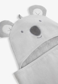 Toalla con capucha gris que presenta características de koala, incluyendo orejas y detalles faciales. Tejido suave y texturizado con un forro interior liso.