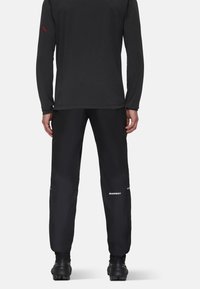Zwarte outdoorbroek gemaakt van duurzaam materiaal, met een slim fit, reflecterende accenten en een logo op het onderbeen.
