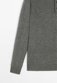 Pullover grigio a maglia con colletto, due bottoni e maniche lunghe. Texture liscia e variazione di colore sottile in tutto il tessuto.