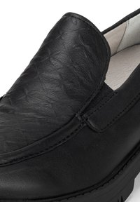 Schwarzer Slipper aus strukturiertem Leder mit glatter Oberfläche, ausgestattet mit elastischen Seiteneinsätzen und einer Gummisohle mit Profil.