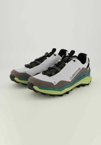 Trailrunning-Schuhe mit einem weißen Textil-Obermaterial, grauen Wildleder-Akzenten, grünen Details und schwarzen Gummisohlen mit strukturiertem Profil.