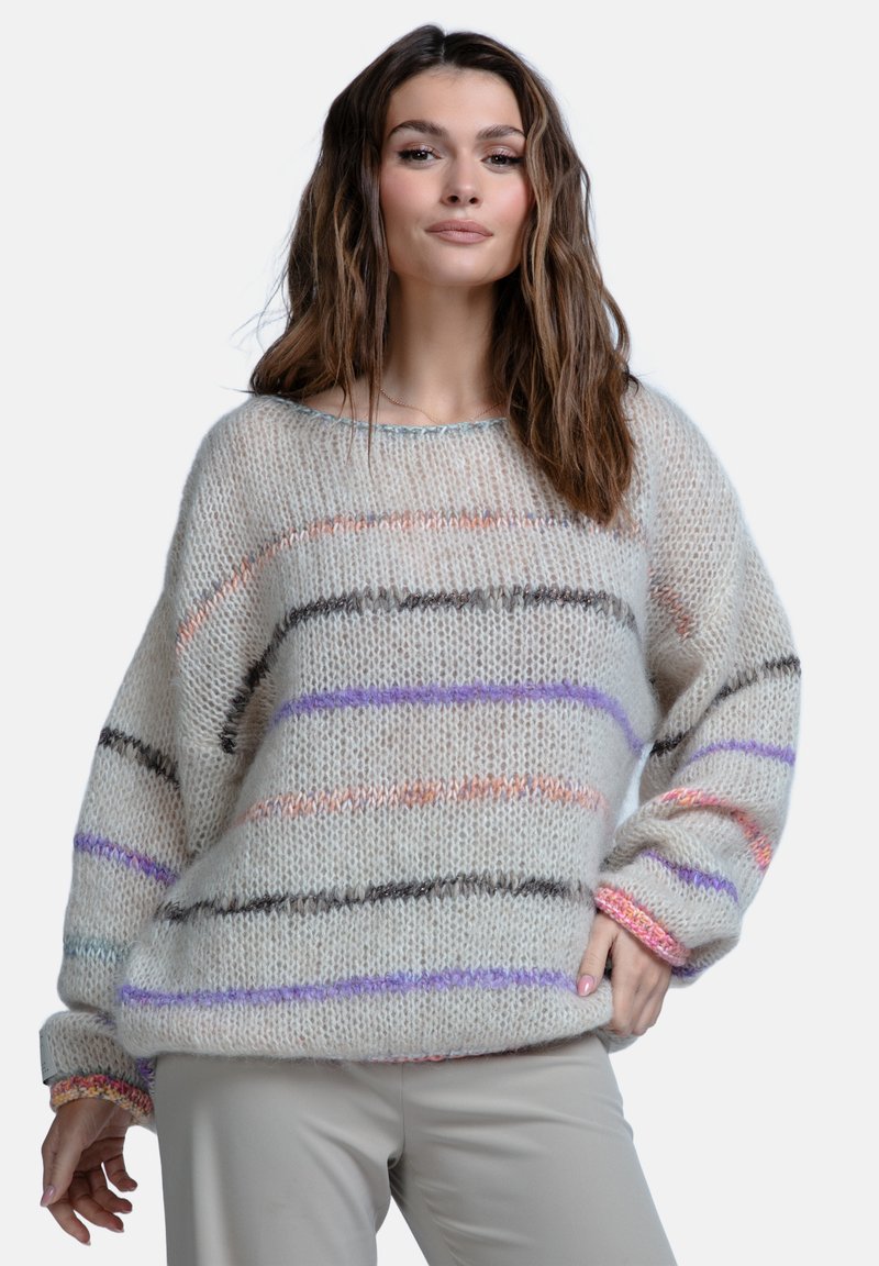 Gruby sweter dzianinowy w jasnym beżu z poziomymi paskami w kolorze fioletowym, pomarańczowym i brązowym. Oversize'owy krój, ściągacze przy mankietach oraz miękka tekstura.