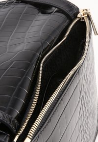 Borsa a mano in pelle nera con trama testurizzata effetto coccodrillo, dettagli con cerniera dorata e interno foderato in morbido tessuto nero.