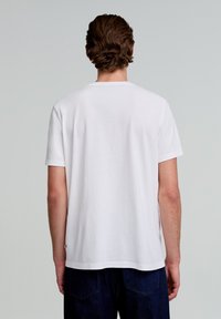 Witte katoenen t-shirt met korte mouwen, een ronde hals en een relaxte pasvorm. Gladde textuur; eenvoudig ontwerp zonder zichtbare patronen of accenten.