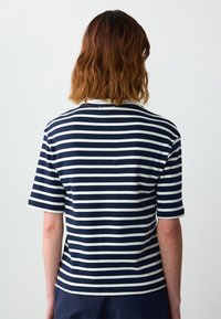 Marineblauwe en witte gestreepte polo met korte mouwen en een kraag. De stof lijkt glad met een reguliere pasvorm. Minimalistisch ontwerp, geen zichtbare logo's.