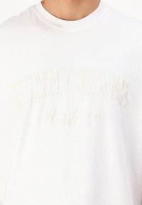 Witte katoenen t-shirt met geborduurde tekst "TOMMY JEANS" en "New York" in bijpassende kleur. Ronde hals en een zachte textuur.