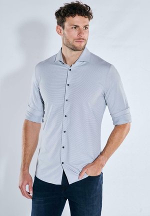 Hellgraues Hemd mit Knopfleiste, dezent gestreift, hochgekrempelte Manschetten und schwarzen Knöpfen. Hergestellt aus einem glatten, leichten Stoff.