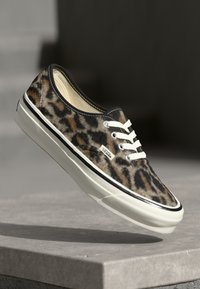 Leopard-print canvas sneaker with white laces, rubber sole, and black accents, featuring a rounded toe and a classic low-top design.