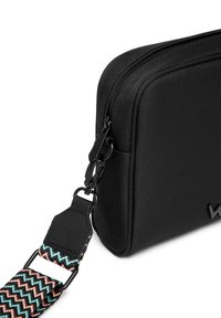 Black fabric shoulder bag with a zip closure, featuring a textured surface and a colorful, patterned adjustable strap with a metal clip.