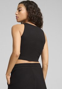 Zwarte geribbelde tanktop met een cropped ontwerp, met een ronde halslijn en brede bandjes; gedragen met bijpassende zwarte broek.