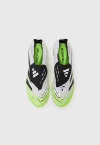 Hvide og sorte sportsko med grønne accenter, der har et strømlinet design, tekstureret overdel og en slip-on konstruktion for nem påtagning.