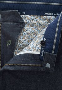 Dunkelblaue Jeanshosen mit einer Reißverschlusstasche, die mit einem Innenfutter aus geometrischen Mustern in Blau, Braun und Beige versehen sind. MEYER ACTIVE Etikett sichtbar.