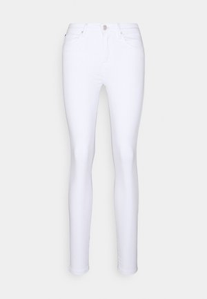 Bílé slim-fit džínsy s předními kapsami, poutky na opasek a knoflíkem se zapínáním na zip, vystavené na neutrálním pozadí.