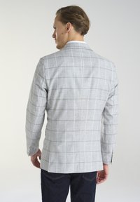 Jasnoszary, kratkowany blazer z cienkimi niebieskimi i żółtymi liniami, jednorzędowy, o teksturowanej tkaninie, z guzikami na mankietach, noszony na ciemnych dżinsach.