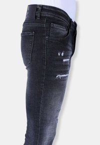 Zwarte denim jeans met een slanke pasvorm, distressed details en lichte vervaging, met een leren patch op de tailleband.