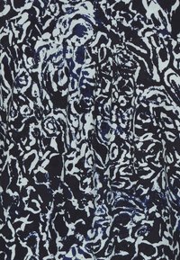 Patrón floral abstracto en blanco y negro con formas en espiral y circulares sobre tela plisada.