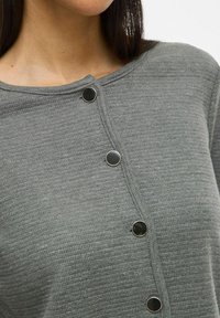 Top de punto gris con escote redondo, tejido texturizado y cinco botones negros a lo largo de la tapeta delantera.