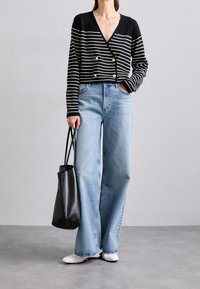 Černobílé pruhované, dvouřadé zkrácené kardigan; světle modré široké kalhoty; černá taška; bílé boty; minimalistický design.